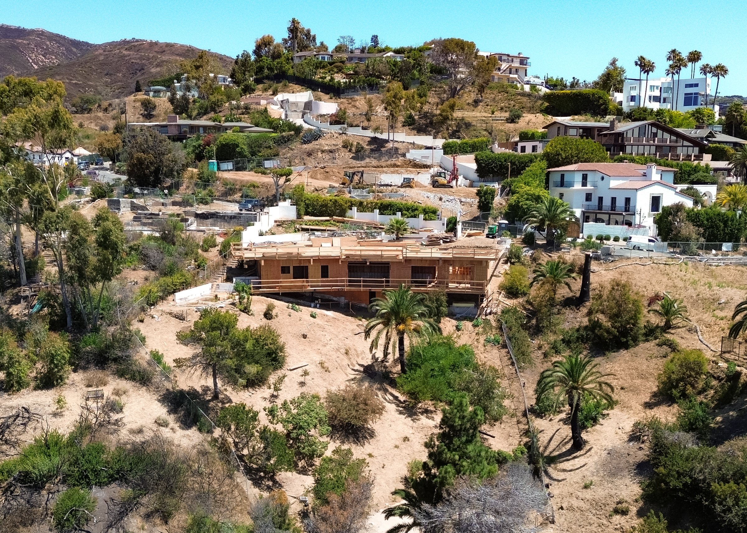 The Pacific Palisades hillside from the air, homes among the canyons above the coast