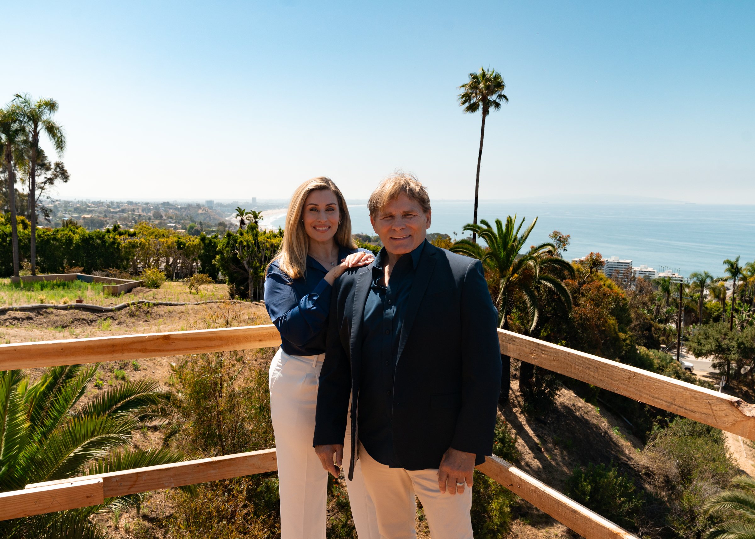 Mike and Christine Ross on the deck of a coastal site, the ocean behind them