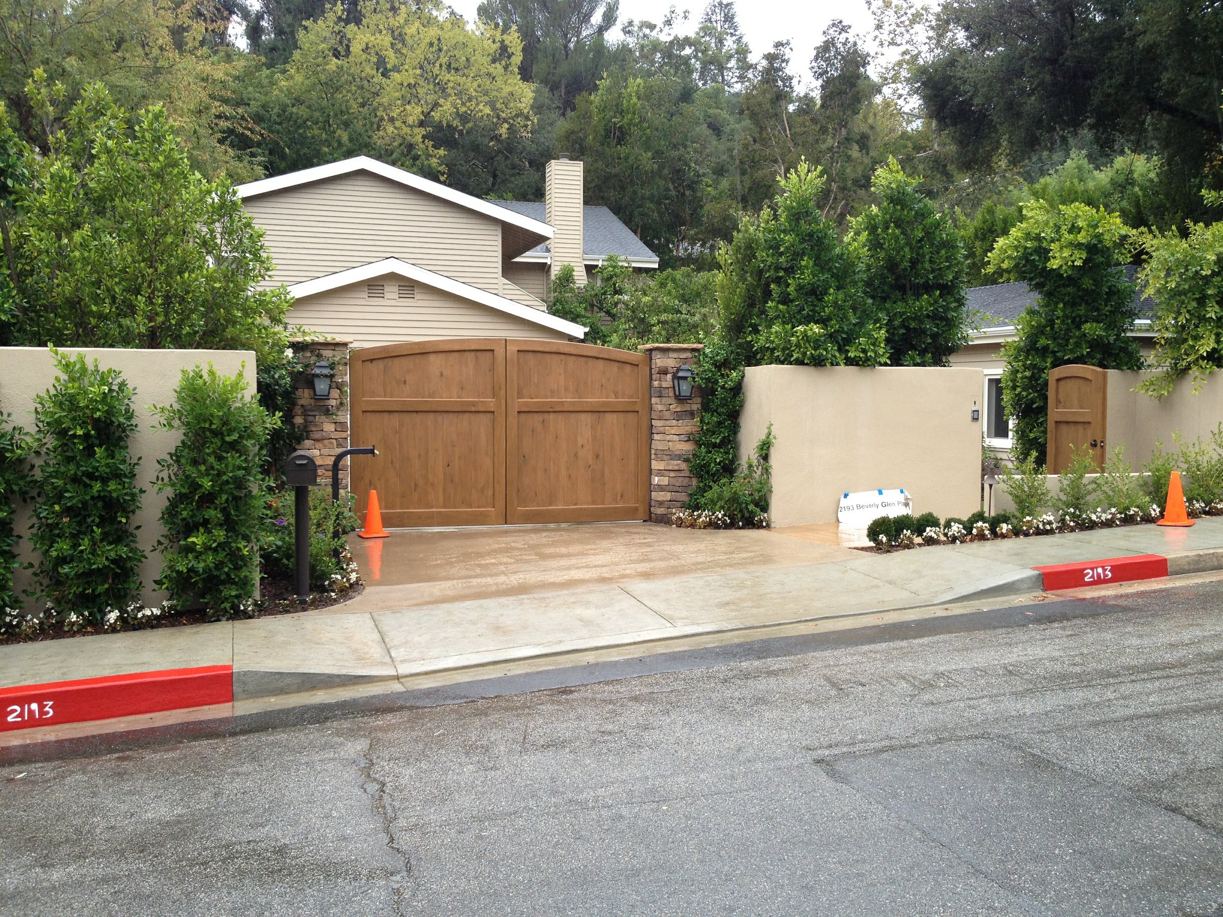 A Bel Air estate exterior in the late afternoon, a long facade under mature trees