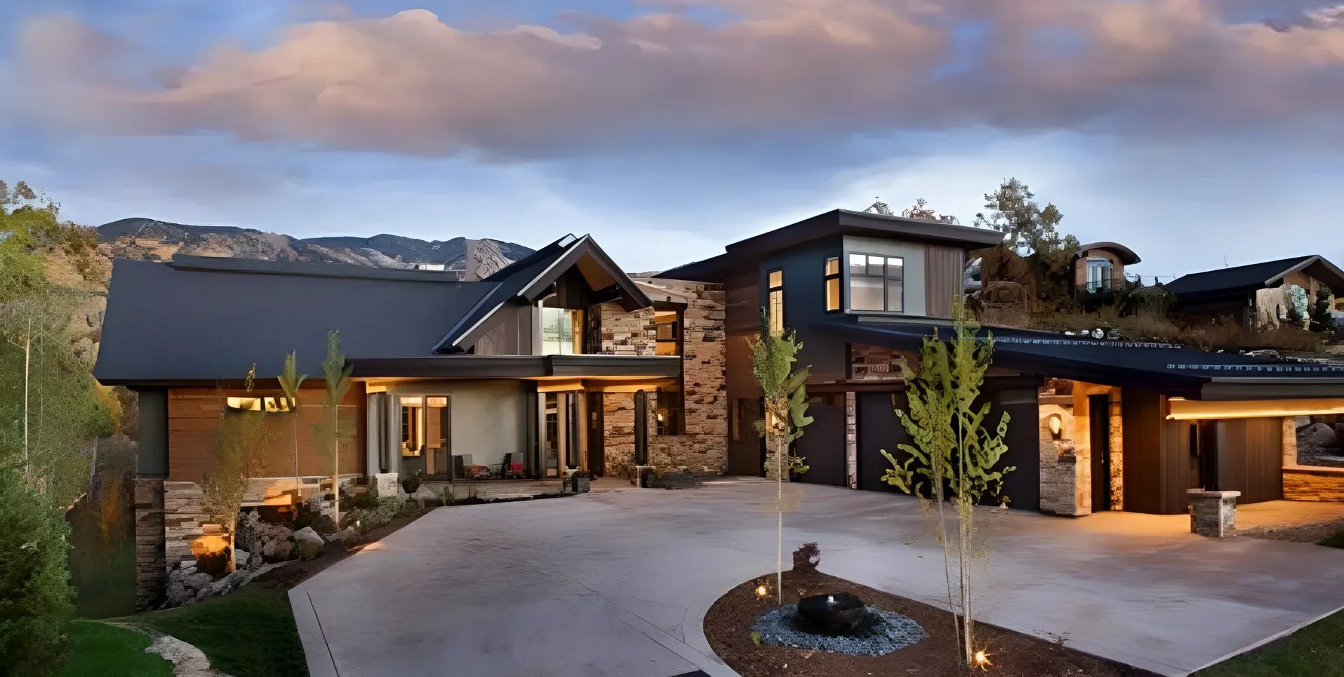 A contemporary Malibu home at dusk, rebuilt after fire, its lights on across the drive